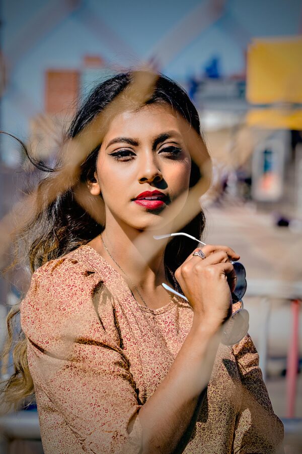 Portrait of a fashionable woman outdoors holding sunglasses.